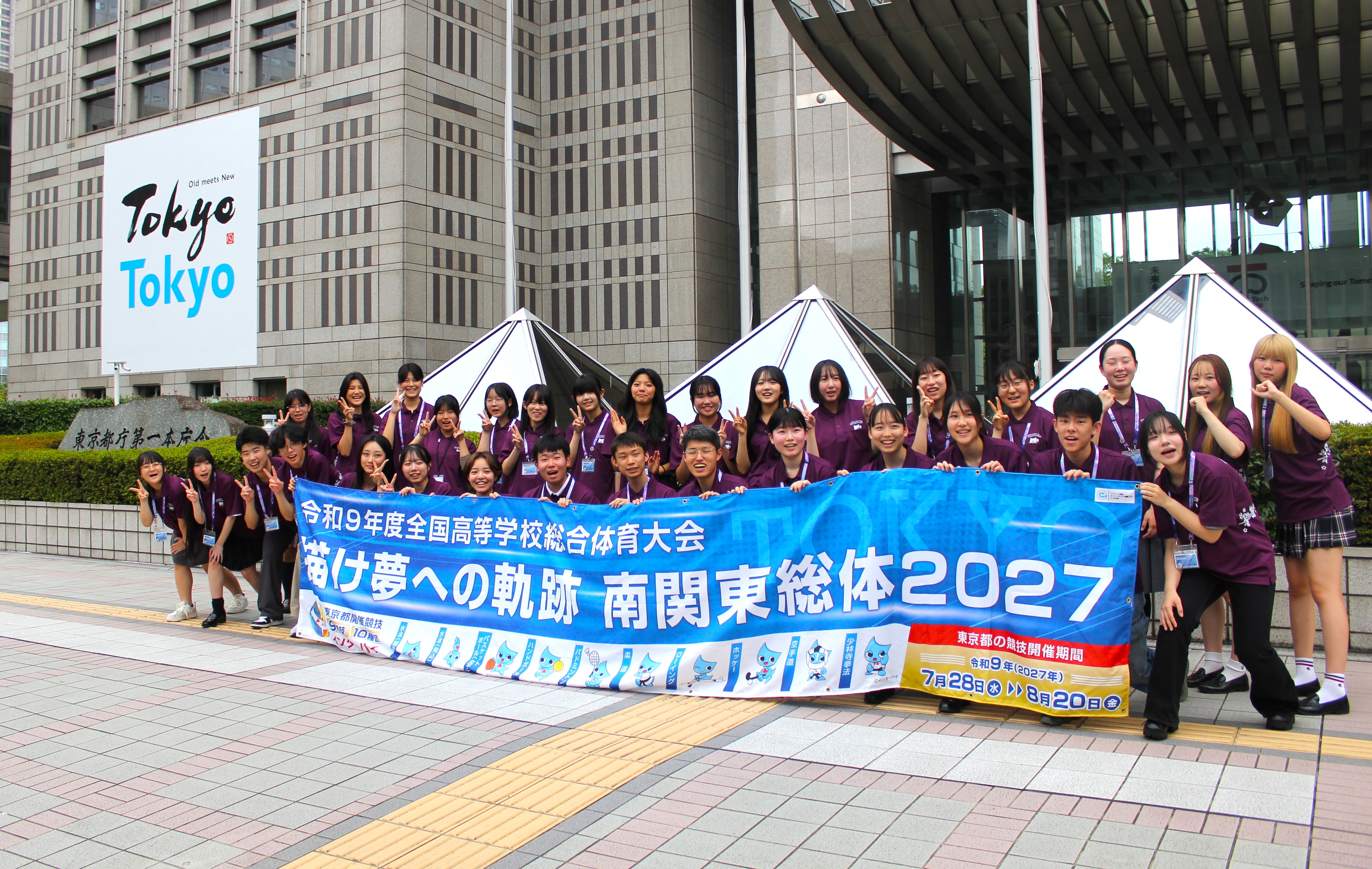 推進委員が東京都第一本庁舎前で集合し、横断幕を持って記念撮影を行う様子