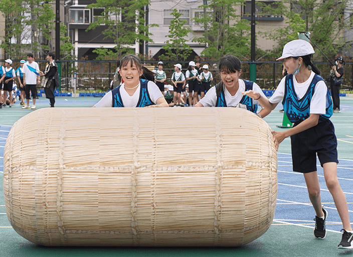 写真：3人で協力してゴールを目指す「大俵転がし」