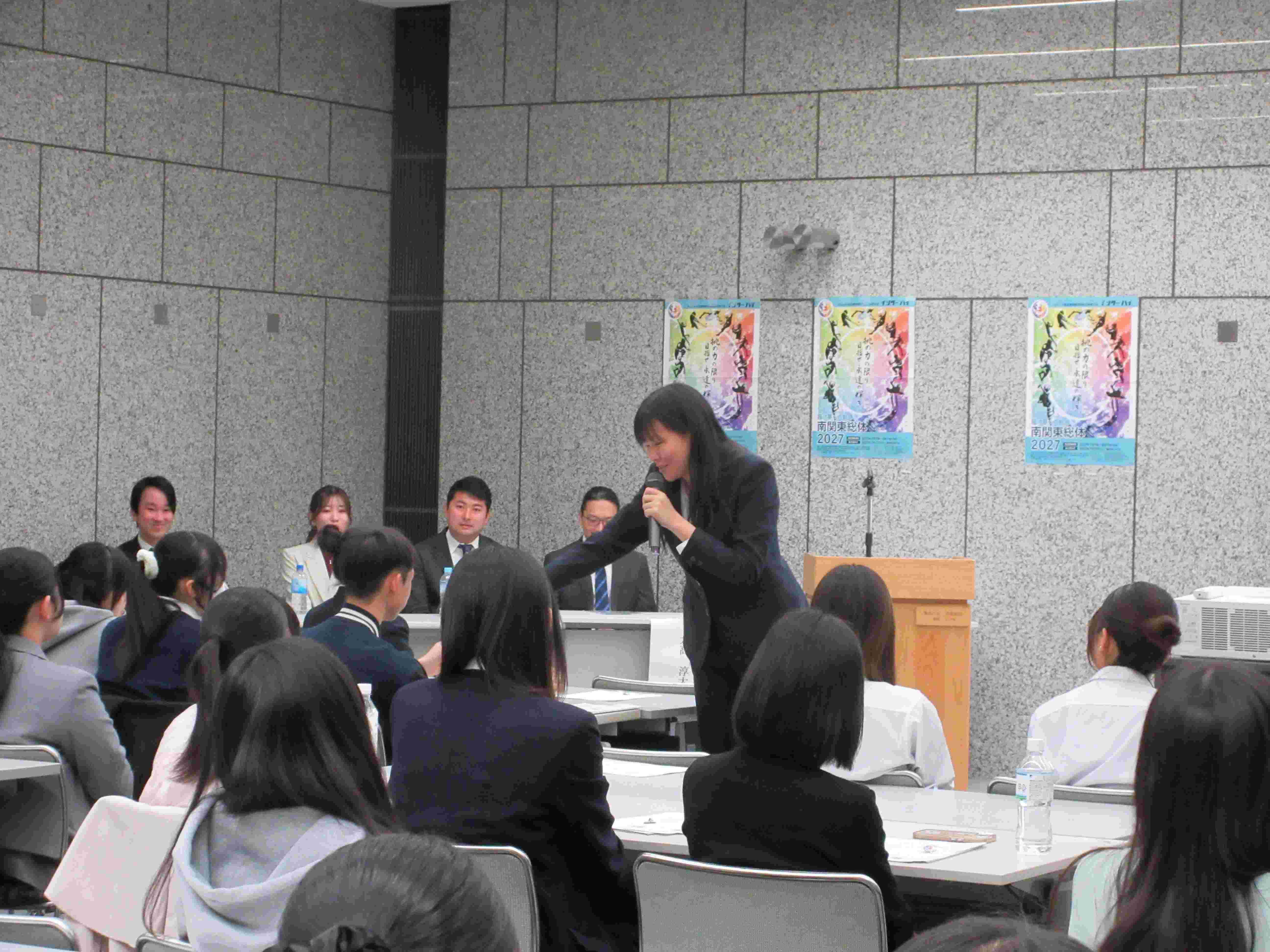 講演中に先輩からマイクを向けられる推進委員